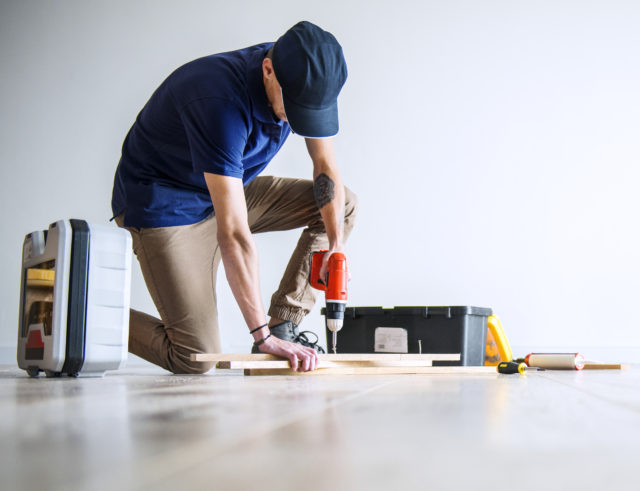 Un homme équipé d'outils réalise des travaux dans une maison