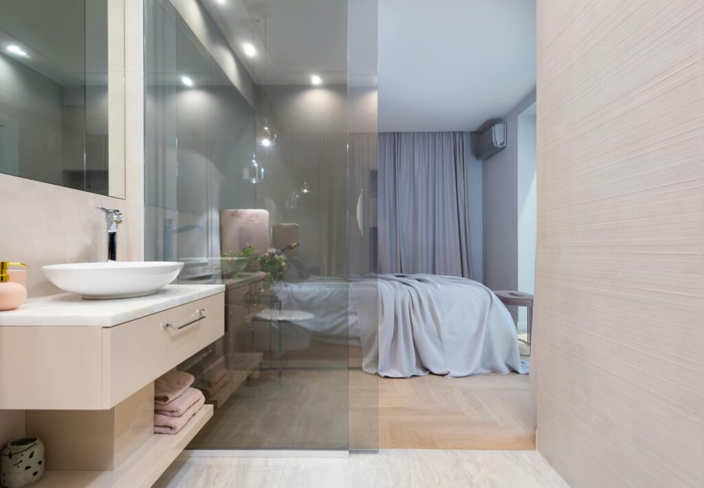 Salle de bain moderne avec vasque et robinet près d’une chambre contemporaine.