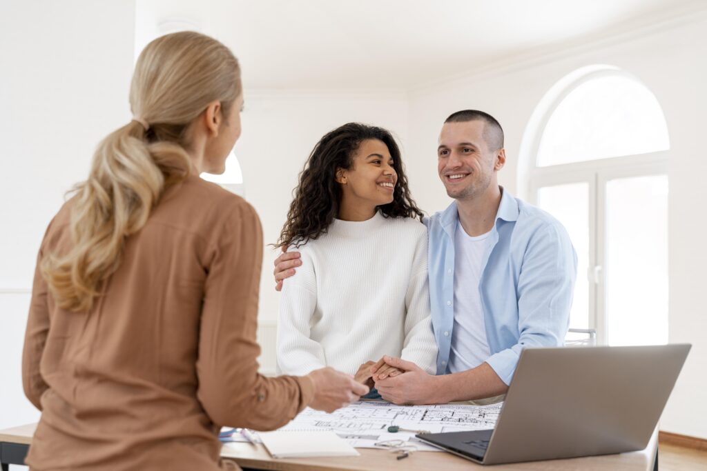 Couple heureux enlacé échangeant avec une agente immobilière.