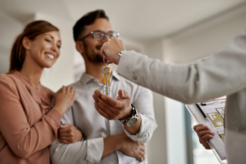 Gros plan sur un agent immobilier remettant les clés d’une nouvelle maison à un couple.