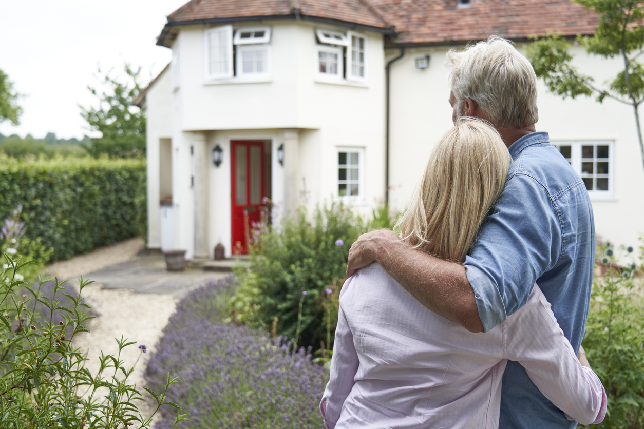 rear view of mature couple standing in garden look at dream home in countryside