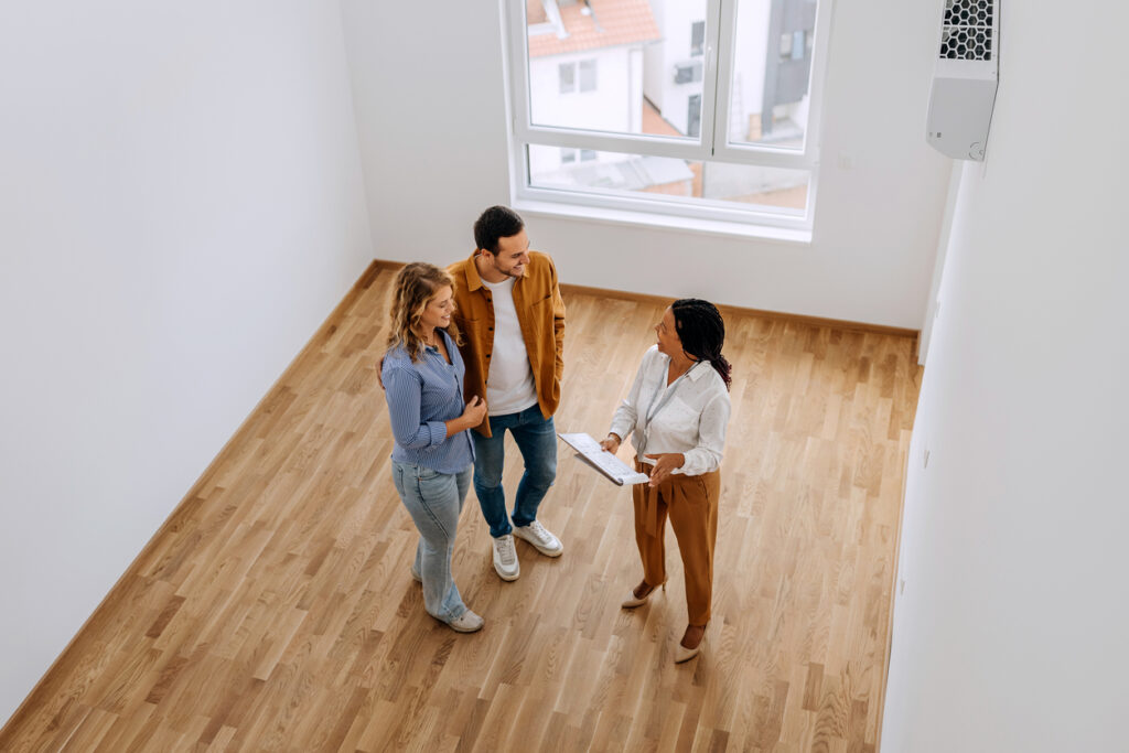high angle view of real estate agent talking with young couple at empty apartment